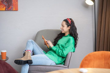 One woman looking into a tablet computer sitting in an armchair.