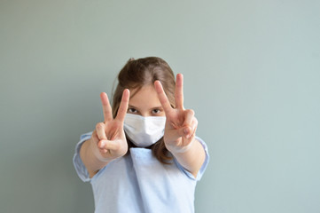 Victory sign shown by girl wearing surgical mask 