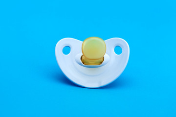 a blue baby pacifier made of soft silicone  isolated on blue background front view with copy space.