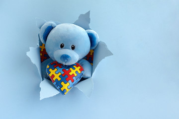 World Autism Awareness, concept with teddy bear holding puzzle or jigsaw pattern on heart in papaer...
