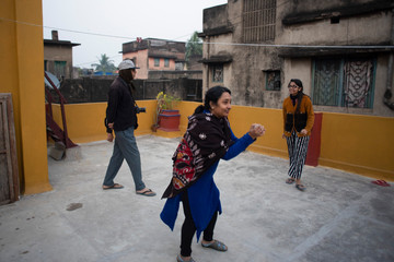 Obraz premium A cheerful Indian Bengali family in winter garments enjoying in a sunny winter afternoon by playing football on a rooftop. Indian lifestyle.
