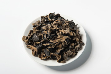 Dried agaric is isolated in a wooden bowl on a white background. Tile (top) driven fengus