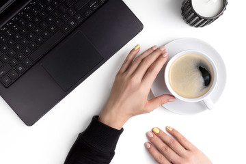 Manicured woman's hands holding cup of coffee on a workplace