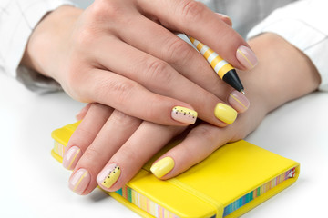 Manicured woman's hands holding a pen and notepad