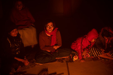 Obraz premium A cheerful Indian Bengali brunette family in winter wear enjoying bonfire on rooftop in the evening. Indian lifestyle and winter.