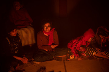 Fototapeta na wymiar A cheerful Indian Bengali brunette family in winter wear enjoying bonfire on rooftop in the evening. Indian lifestyle and winter.