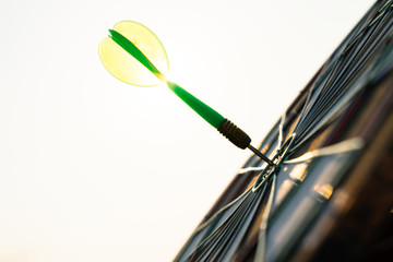 Green darts arrows in the target center on the sky background. Business target or goal success and winner concept.
