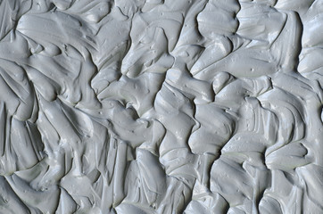 Obraz premium Gray bentonite facial clay (mask, face cream, body wrap) texture close up, selective focus. Abstract background with brush strokes.