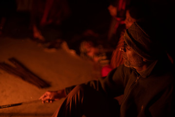 A cheerful Indian Bengali brunette family in winter wear enjoying bonfire  on rooftop in the evening. Indian lifestyle and winter.