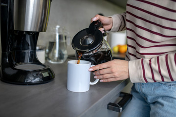 Woman hands pouring coffee into white cup