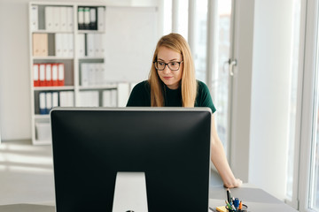 Young businesswoman standing at her computer