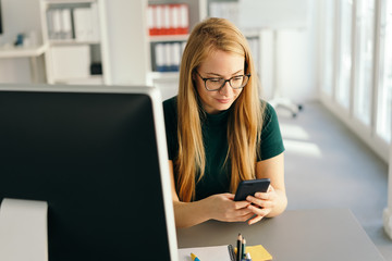 Young businesswoman sending a text message