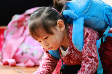 A little girl lying flat on her stomach reading a book