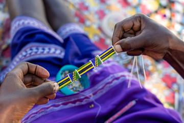 Making of handmade jewellery. Masai african women hands, top view, close up. Island of Zanzibar, Tanzania, Africa - obrazy, fototapety, plakaty