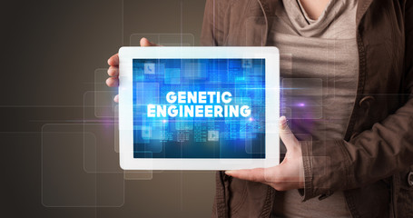 Young business person working on tablet and shows the inscription: GENETIC ENGINEERING