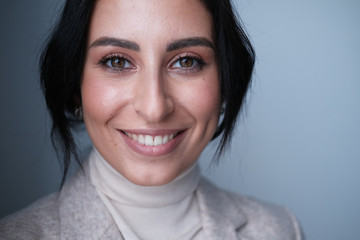 A large portrait of a middle-aged woman (30-35 years old) with dark hair and brown eyes in light clothes, with a smile. 