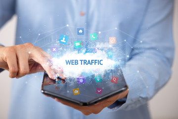 Businessman holding a foldable smartphone with WEB TRAFFIC inscription, technology concept