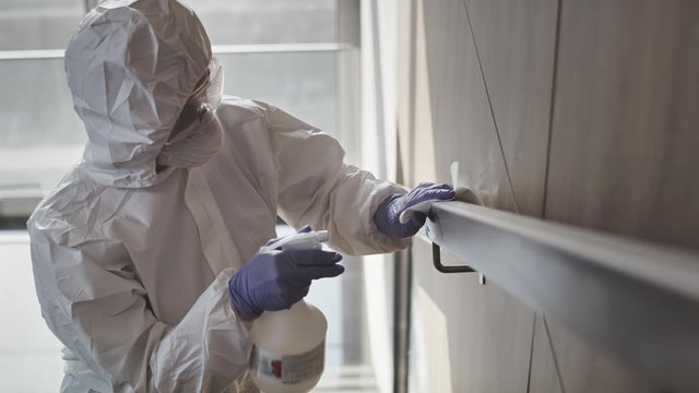 Video of a person in clean suit disinfecting a handrail. Shot with RED helium camera in 8K.