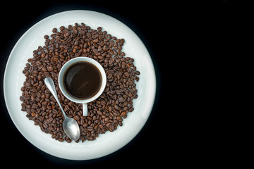 Commercial image to add text of cup of coffe on several coffee beans, on a big round plate. Black background