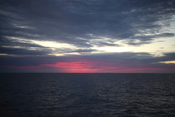 Fototapeta na wymiar Beautiful red colorful sunrise at the sea with dramatic clouds and sun shining