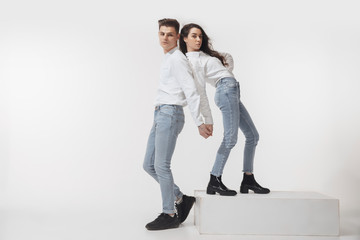In white. Trendy fashionable couple isolated on white studio background. Caucasian woman and man posing in basic minimal unisex clothes. Concept of relations, fashion, beauty, love. Inclusive.