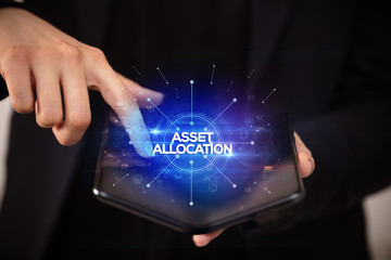 Naklejka premium Businessman holding a foldable smartphone with ASSET ALLOCATION inscription, new business concept
