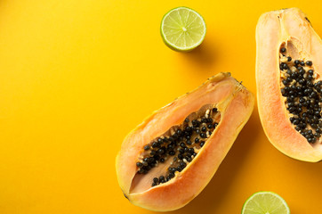 Summer composition. Tropical lime and papaya fruits cut in half lie on a yellow background. Summer concept. Flat lay, copy space