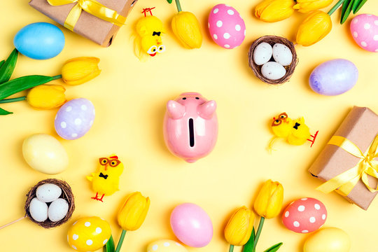 Piggy bank surrounded by eggs and Easter decoration on a yellow background. - Powered by Adobe
