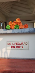 Closeup of colorful towels and no lifeguard on duty warning sign at swimming pool.  Safety concept..