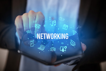 Businessman holding a foldable smartphone with NETWORKING inscription, social media concept