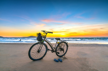 Fototapeta na wymiar A bike by the beautiful beach at dawn, this is a means for a coastal walk of fishermen
