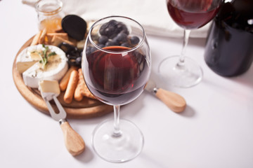Two glass of red wine and plate with assorted cheese, fruit and other snacks for party
