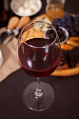 glass of red wine and plate with assorted cheese, fruit and other snacks for party