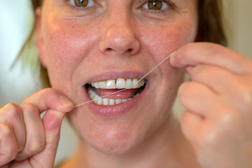 Middle-aged woman flossing her teeth