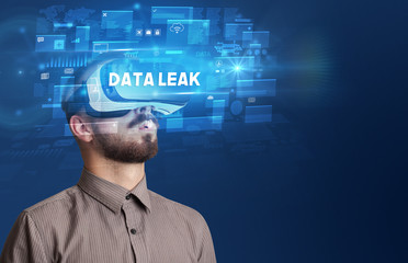 Businessman looking through Virtual Reality glasses with DATA LEAK inscription, innovative security concept