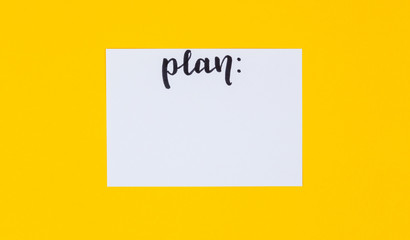 Wide view image of blank white paper and black calligraphic inscription plan on yellow background