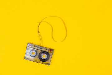 Top view of audio cassette with tangled tape on bright yellow background with copy space,...