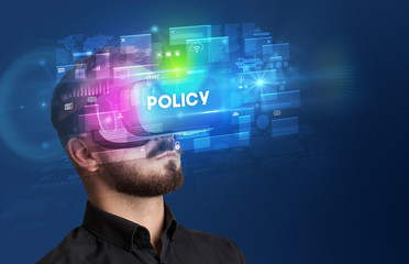 Businessman looking through Virtual Reality glasses with POLICY inscription, innovative security concept