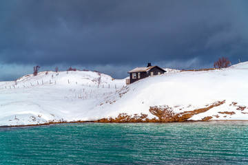 Brensholmen, Troms og Finnmark / Norway: Small wooden house in a snowy coastal scenery