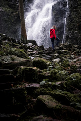 Weitwinkel frau vor Wasserfall klettert auf Felsen