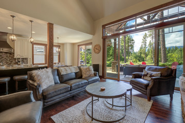 An absolute beautiful luxury living room with huge vaulted  ceiling, fire place, harwood floor, amazing furniture, and lots of windows and doors.