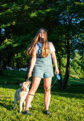 young attractive blond woman playing with her dog in green park at summer, lifestyle people concept