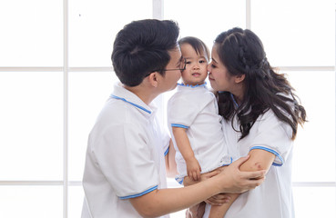 Asian young family together feeding adorable cute girl at home, father making small business marketing online logistic home office, mother playing with the child, parenthood duty multi task concept