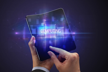 Obraz premium Businessman holding a foldable smartphone with COMPUTING inscription, new technology concept