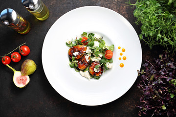 Caramelized figs on lettuce with goat cheese. A plate with an appetizing dish. Application suggestion. Culinary photography, food stylization.