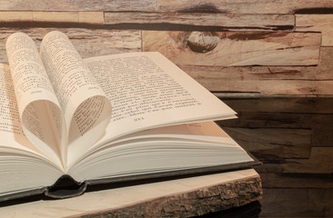  Livre plié en forme de cœur sur fond de bois.