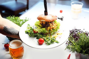 Tasty burger with pulled beef and cheese. A plate with an appetizing dish. Application suggestion. Culinary photography, food stylization.