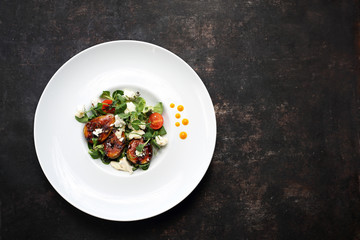 Caramelized figs on lettuce with goat cheese. A plate with an appetizing dish. Application suggestion. Culinary photography, food stylization.