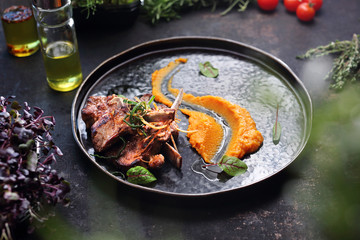 Lamb with carrot mousse. A plate with an appetizing dish. Application suggestion. Culinary photography, food stylization.