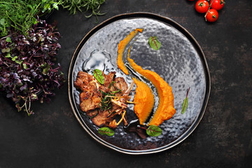 Baked lamb ribs with orange vegetable mousse. A plate with an appetizing dish. Application suggestion. Culinary photography, food stylization.